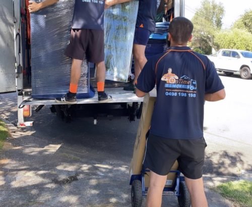 Experienced moving team loading furniture into a removalist truck