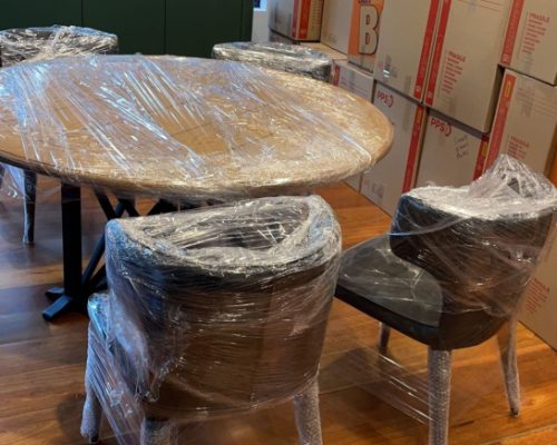 Professional movers transporting dining tables, chairs and household items